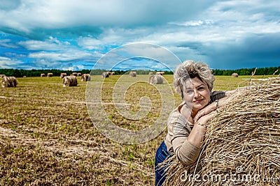 Mature beautiful woman with a bouquet of wild flowers on a mown wheat field. Active recreation, perfect maturity Stock Photo