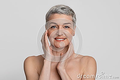 Mature Beauty. Portrait Of Nude Beautiful Middle-Aged Woman Touching Her Smooth Skin Stock Photo