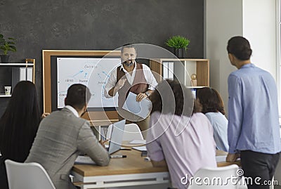 Mature business coach explaining to a group of young people how to reach success Stock Photo