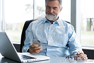 Mature business man in formal clothing using mobile phone. Serious businessman using smartphone at work. Manager in suit Stock Photo