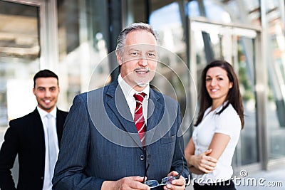 Mature businessman in front of a group of business people outdoor Stock Photo