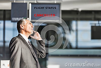 Mature businessman making report on his cancelled flight while standing at his boarding gate in airport Stock Photo