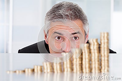 Mature businessman with stack of coins Stock Photo