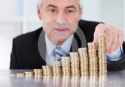 Mature businessman with stack of coins Stock Photo