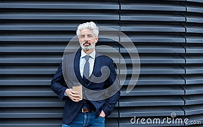 A mature businessman standing outdoors, holding coffee. Copy space. Stock Photo