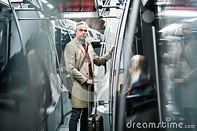 Mature businessman with suitcase travelling by subway in city. Stock Photo