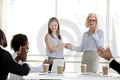 Mature businesswoman shaking hand of employee at company briefing Stock Photo