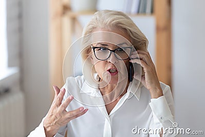 Mature businesswoman talking by phone arguing with client feels irritated Stock Photo