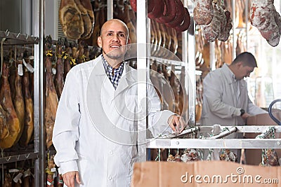Mature butcher hanging wurst and jamon joints Stock Photo