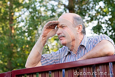 Mature caucasian man carefully watching over the fence. Stock Photo