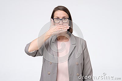 Mature caucasian woman in glasses covering mouth. I will not tell this secret anybody Stock Photo