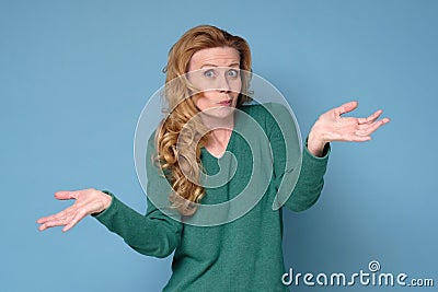Mature caucasian woman shrugs her shoulders having some doubts. Stock Photo