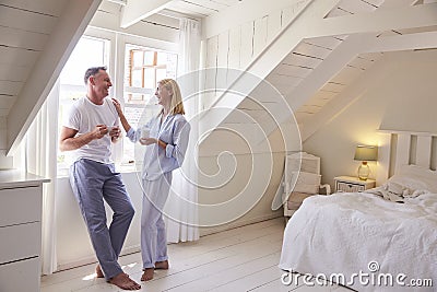 Mature Couple Standing By Bedroom Window With Hot Drink Stock Photo