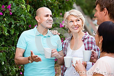 Mature couples walking and drinking coffee on holiday Stock Photo