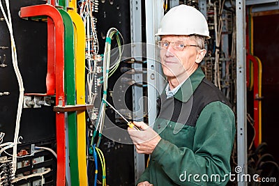 Mature electrician working in hard hat with cables Stock Photo