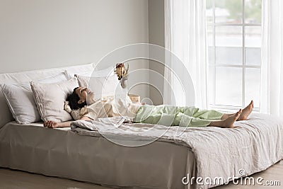 Mature female in pajama lying down on bed Stock Photo