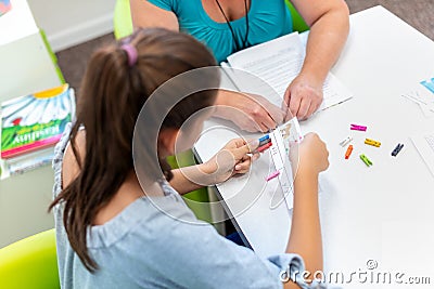 Mature female therapist working with a teenage girl with learning difficulties to master logical tests. Stock Photo