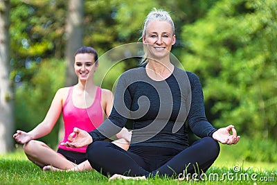 Mature Middle Aged and Young Woman Practicing Yoga Outside Stock Photo