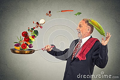 Mature happy businessman cooking vegetables with a pan Stock Photo