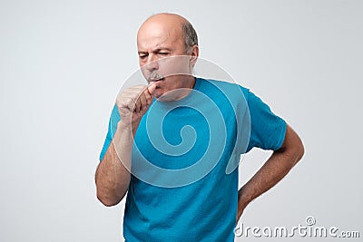 Mature hispanic man in blue t-shirt man coughing being ill. Stock Photo