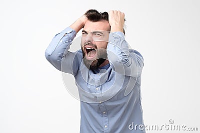 Mature hispanic man pulling his hair in hysteria having troubles at work Stock Photo