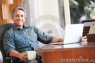 Mature Hispanic Man Using Laptop On Desk At Home Stock Photo