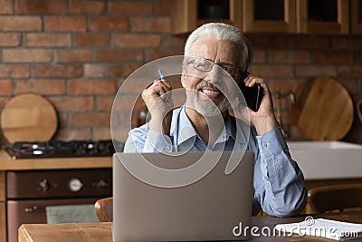 Mature male expert speak by phone distracted from laptop screen Stock Photo