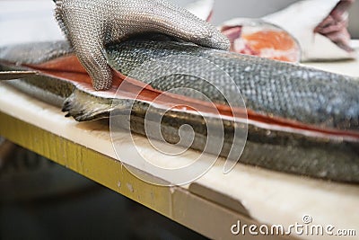 Mature male fishmonger cutting fish on table Stock Photo