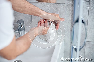 Mature male hands pushing a pump bottle Stock Photo