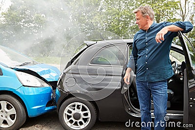 Mature Male Motorist In Crash For Crash Insurance Fraud Getting Out Of Car Stock Photo