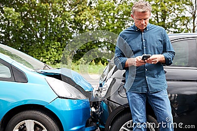 Mature Male Motorist Involved In Car Accident Calling Insurance Company Or Recovery Service Stock Photo