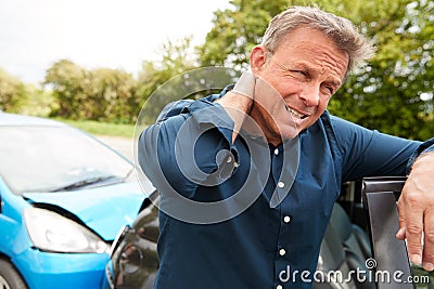 Mature Male Motorist With Whiplash Injury In Car Crash Getting Out Of Vehicle Stock Photo