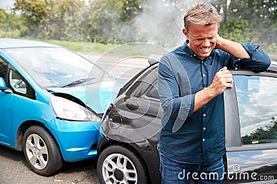 Mature Male Motorist With Whiplash Injury In Car Crash Getting Out Of Vehicle Stock Photo