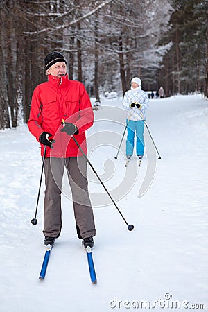 Mature male skier and woman stay on skis in winter snow skiing run Stock Photo