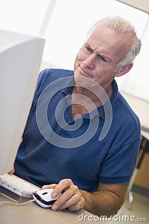 Mature male student frowning at computer monitor Stock Photo