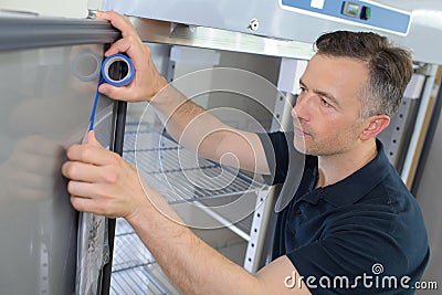 Mature male technician measuring fridge Stock Photo