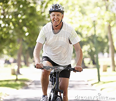 Mature Man Cycling Through Park Stock Photo