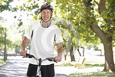 Mature Man Cycling Through Park Stock Photo