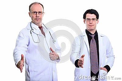 Mature man doctor and young man doctor giving handshake together Stock Photo