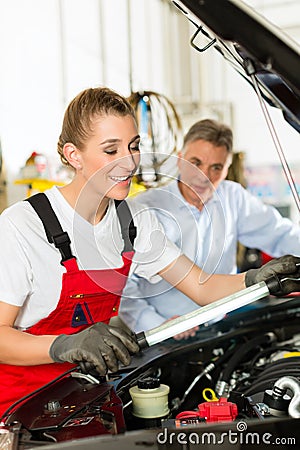 Mature man and female car mechanic in workshop Stock Photo