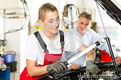 Mature man and female car mechanic in workshop Stock Photo