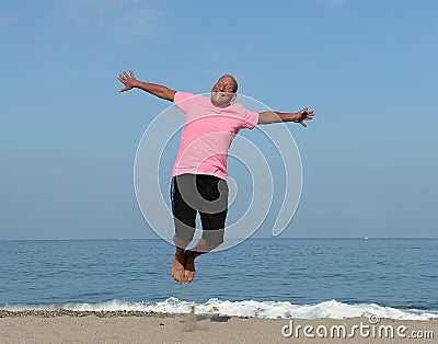 Mature man jumping on beach Stock Photo