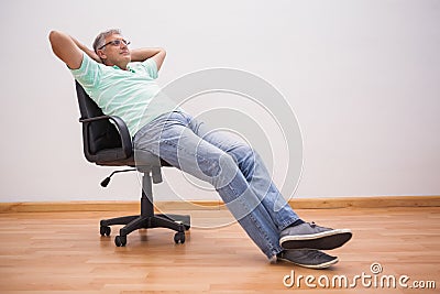 Mature man leaning back in swivel chair Stock Photo