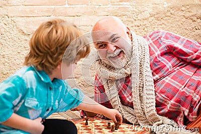 Mature man with little boy playing chess. Chess competition. Senior man thinking about his next move in a game of chess Stock Photo