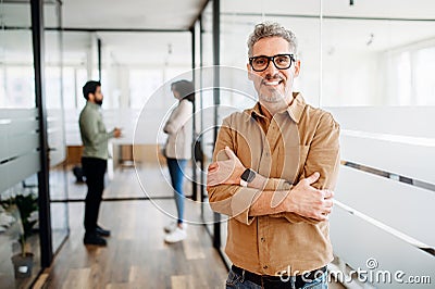 Mature man manager with a genial smile crosses his arms in satisfaction Stock Photo