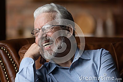 Mature man sit on sofa laugh demonstrate healthy straight teeth Stock Photo