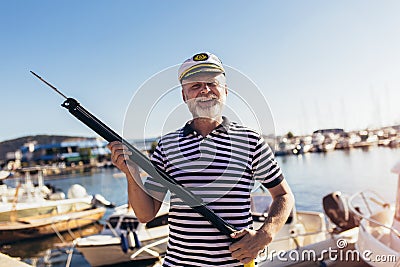 Man standing near the sea dressed in a sailor`s shirt and hat holding a harpoon Stock Photo