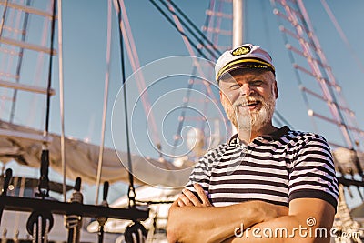Man stands on pier dressed in a sailor`s shirt and hat Stock Photo