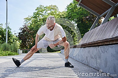 Mature man stretching body and feeling flexible while exercising at the park Stock Photo