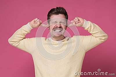 Mature man suffering from loud music and pain trying to plug ears Stock Photo